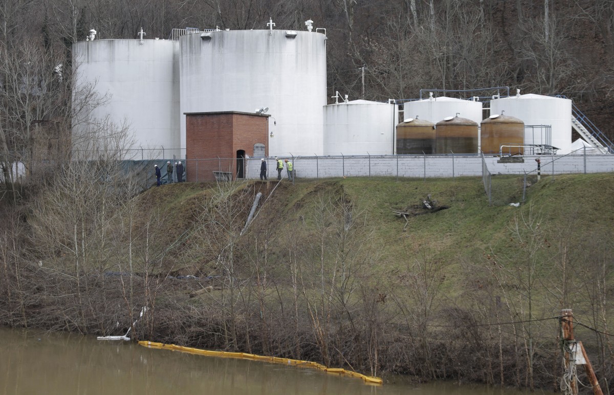 Workers inspect an area outside a retaining wall around storage tanks where a chemical leaked into the Elk River at Freedom Industries storage facility in Charleston, W.Va., Monday, Jan. 13, 2014. The ban on tap water for parts of West Virginia was lifted on Monday, ending a crisis for a fraction of the 300,000 people who were told not to drink, wash or cook with water after the chemical spill tainted the water supply. Gov. Earl Tomblin made the announcement at a news conference, five days after people were told to use the water only to flush their toilets. (AP Photo/Steve Helber)