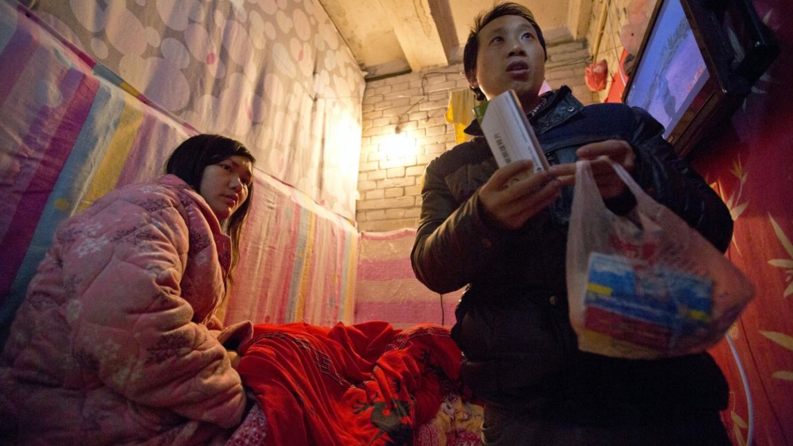 In this Jan. 4, 2014 photo, Wu Yongyuan, right, shows medicines his wife Gong Qifeng, left, takes to control her schizophrenia symptoms, in a room they rent in Beijing for stay as Wu keeps petitioning to China's central government for help. When Gong's mind is clear, she can recall how she begged for mercy. Several people pinned her head, arms, knees and ankles to a hospital bed before driving a syringe of labor-inducing drugs into her stomach. She was seven months pregnant with what would have been her second boy. The drugs caused her to have a stillborn baby after 35 hours of excruciating pain. Since the abortion more than two years ago, Gong has been diagnosed with schizophrenia. (AP Photo/Alexander F. Yuan)