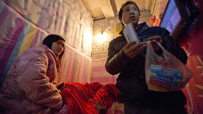 In this Jan. 4, 2014 photo, Wu Yongyuan, right, shows medicines his wife Gong Qifeng, left, takes to control her schizophrenia symptoms, in a room they rent in Beijing for stay as Wu keeps petitioning to China's central government for help. When Gong's mind is clear, she can recall how she begged for mercy. Several people pinned her head, arms, knees and ankles to a hospital bed before driving a syringe of labor-inducing drugs into her stomach. She was seven months pregnant with what would have been her second boy. The drugs caused her to have a stillborn baby after 35 hours of excruciating pain. Since the abortion more than two years ago, Gong has been diagnosed with schizophrenia. (AP Photo/Alexander F. Yuan)