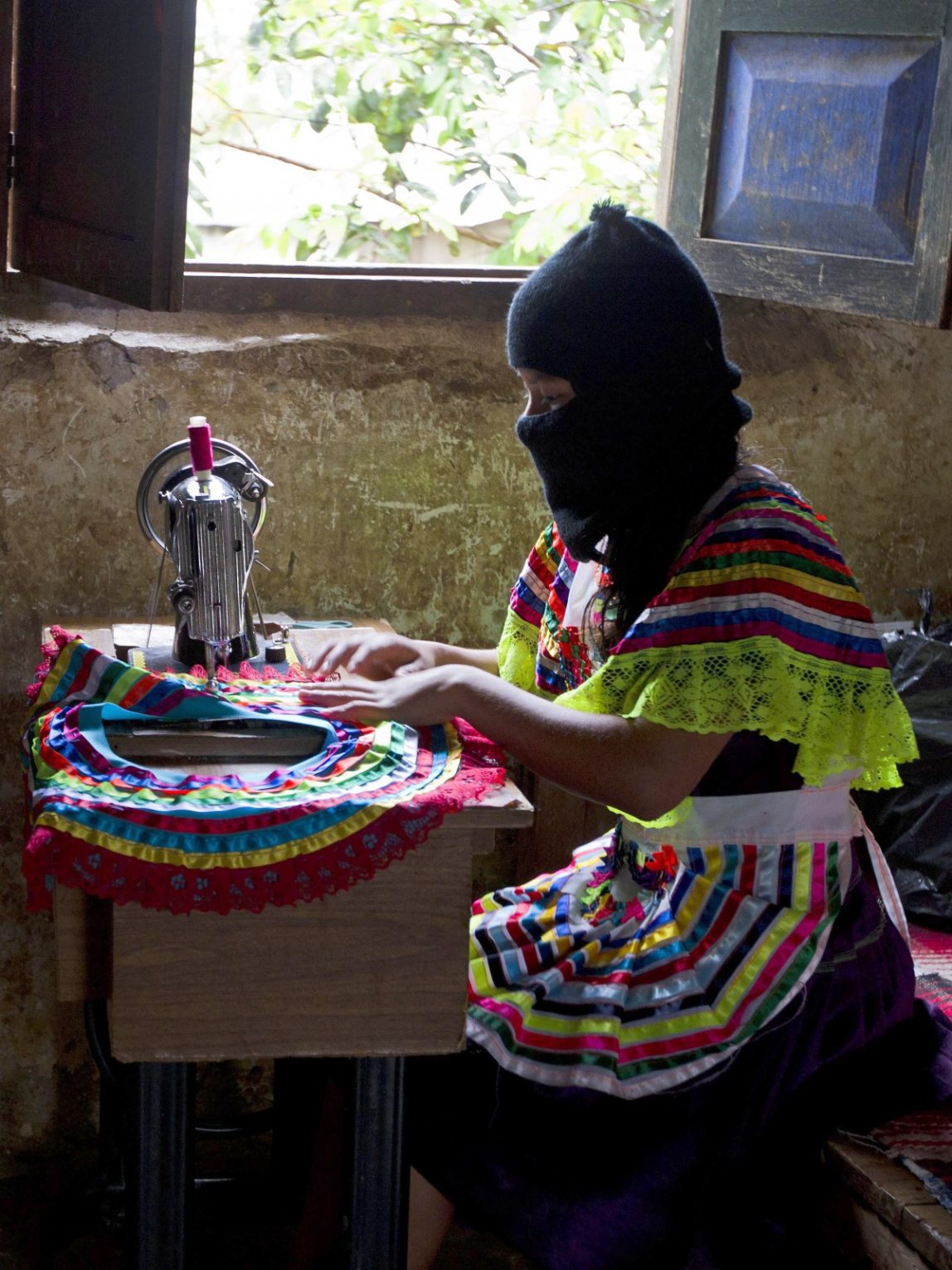 In this Dec. 27, 2013 photo, a woman sews part of a traditional skirt in the Zapatista controlled community of La Garrucha, Mexico. Since their uprising 20 years ago, Zapatistas, known by their initials as the EZLN, have lived in secretive, closed-off enclaves they have formed in the half-dozen communities they hold. But in the last five months the rebels have opened up their communities to more than 7,000 Mexicans and foreigners interested in learning about how they self-govern and maintain their independence and way of life. Those invited stayed for a week at a time and lived with a Zapatista family. Members of these communities wear masks to hide their identities when outsiders, interested in learning about how they self-govern and maintain their way of life, gain access to visit them. (AP Photo/Christian Palma)