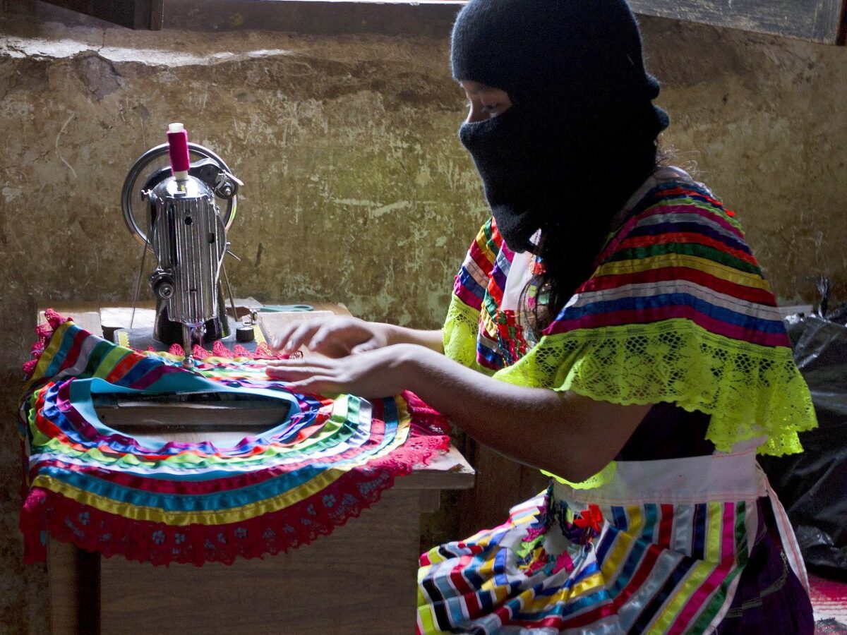 In this Dec. 27, 2013 photo, a woman sews part of a traditional skirt in the Zapatista controlled community of La Garrucha, Mexico. Since their uprising 20 years ago, Zapatistas, known by their initials as the EZLN, have lived in secretive, closed-off enclaves they have formed in the half-dozen communities they hold. But in the last five months the rebels have opened up their communities to more than 7,000 Mexicans and foreigners interested in learning about how they self-govern and maintain their independence and way of life. Those invited stayed for a week at a time and lived with a Zapatista family. Members of these communities wear masks to hide their identities when outsiders, interested in learning about how they self-govern and maintain their way of life, gain access to visit them. (AP Photo/Christian Palma)