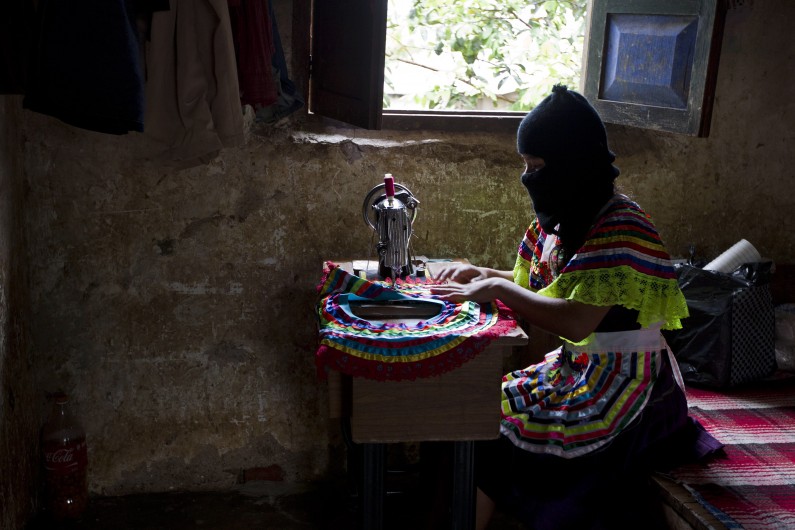 In this Dec. 27, 2013 photo, a woman sews part of a traditional skirt in the Zapatista controlled community of La Garrucha, Mexico. Since their uprising 20 years ago, Zapatistas, known by their initials as the EZLN, have lived in secretive, closed-off enclaves they have formed in the half-dozen communities they hold. But in the last five months the rebels have opened up their communities to more than 7,000 Mexicans and foreigners interested in learning about how they self-govern and maintain their independence and way of life. Those invited stayed for a week at a time and lived with a Zapatista family. Members of these communities wear masks to hide their identities when outsiders, interested in learning about how they self-govern and maintain their way of life, gain access to visit them.  (AP Photo/Christian Palma)