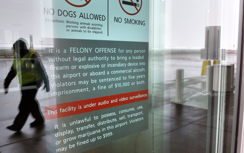 A security officer walks near a notice prohibiting marijuana possession at Denver International Airport, Monday, Jan. 27, 2014. Carrying marijuana through airport security in Colorado may get the pot confiscated, but there appears to be little danger of legal repercussions. Denver airport spokeswoman Laura Cole said the ban was enacted because Federal agencies operate at the airport and officials there did not want the inevitable conflict between state and federal laws. (AP Photo/Brennan Linsley)