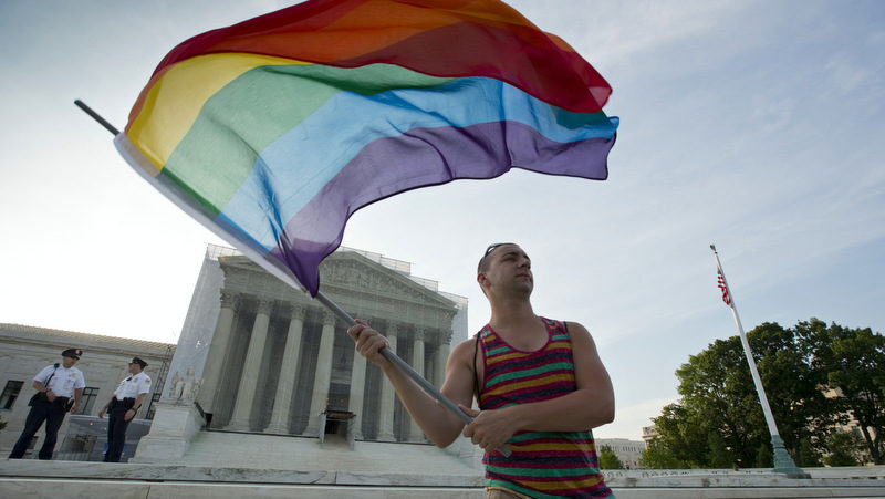 Gay rights advocate Vin Testa waves a rainbow flag in front of the Supreme Court at sun up in Washington, Wednesday, June 26, 2013. (AP Photo/J. Scott Applewhite)