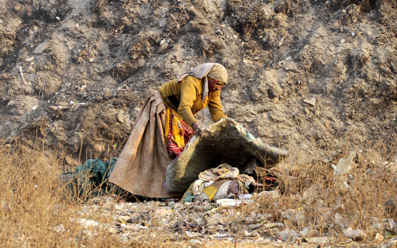 A ragpicker woman salvages reusable items with a backdrop of a mound of garbage on the outskirts of Ahmadabad, India. (AP Photo/Ajit Solanki)