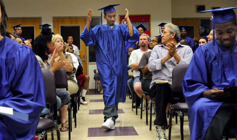 Damon Rodriguez raises his arms as he walks down the aisle during his graduation ceremony