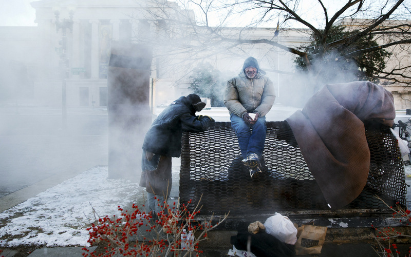 Four homeless men warm themselves on a steam grate by the Federal Trade Commission, blocks from the Capitol, during frigid temperatures in Washington, Saturday, January 4, 2014. A winter storm that swept across the Midwest this week blew through the Northeast on Friday, leaving bone-chilling cold in its wake. (AP Photo/Jacquelyn Martin)