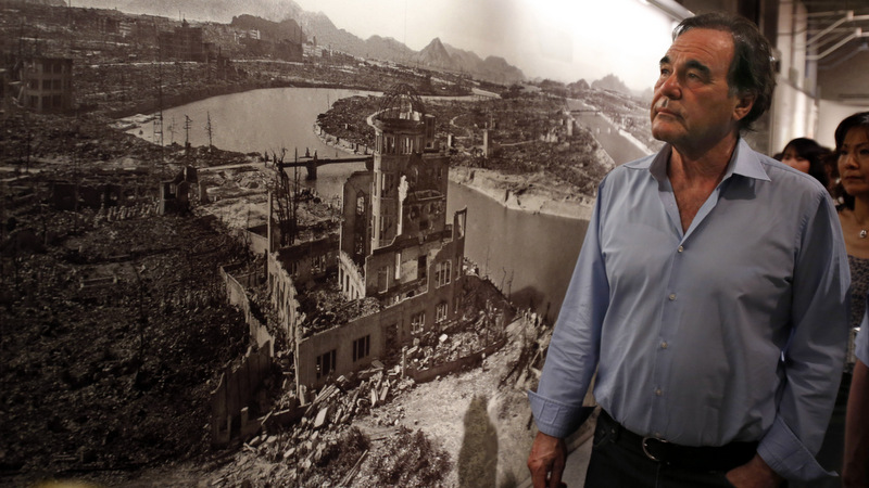 Oliver Stone watches a photo showing the destruction caused by the Aug. 6, 1945 atomic bombing on Hiroshima