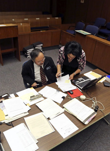In this Wednesday, Jan. 16, 2013 photo, Judge Lance Ito and court clerk Melody Ramirez go over documents in Ito's closed and semi-darkened courtroom, used these days for the processing of paperwork and other duties but not for hearing cases, at the Criminal Justice Center in Los Angeles. (AP Photo/Reed Saxon)