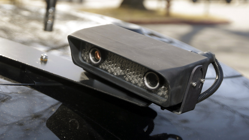 A camera is mounted near the rear window of a police car