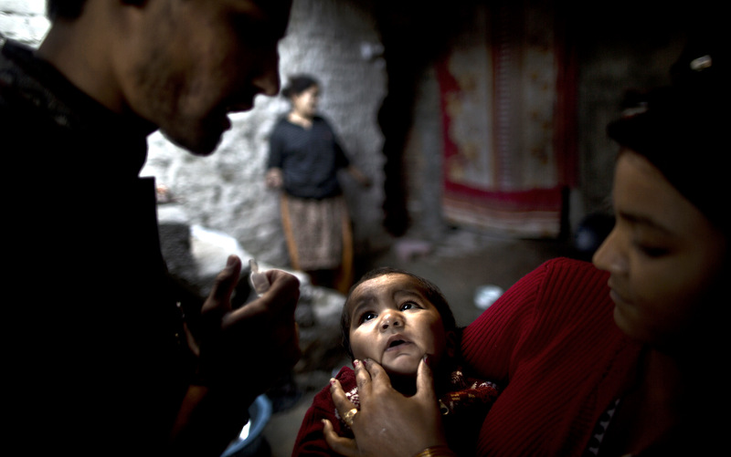 Pakistani Sonya Javed, 20, right, holds her son Shahzeb, 1, to receive a polio vaccine by a health worker at her home in Islamabad, Pakistan. The World Health Organization said the northwestern Pakistani city of Peshawar has become the largest poliovirus reservoir in the world. (AP Photo/Muhammed Muheisen, Nov. 26, 2013)