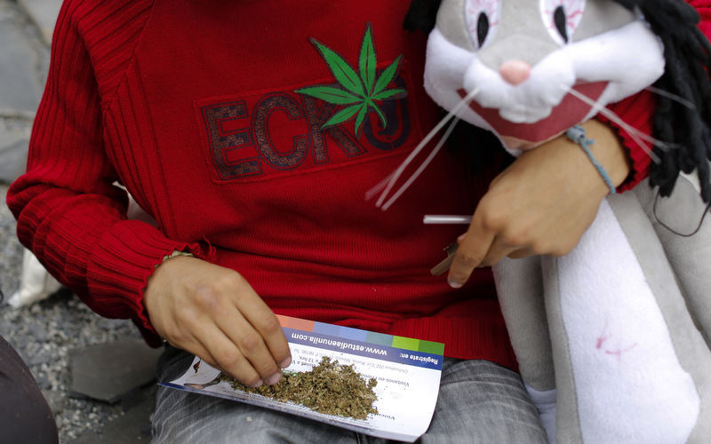 A young man prepares a marijuana joint while holding a Bugs Bunny stuffed animal during a small gathering to demand the legalization of marijuana in Mexico City,  (AP Photo/Dario Lopez-Mills)