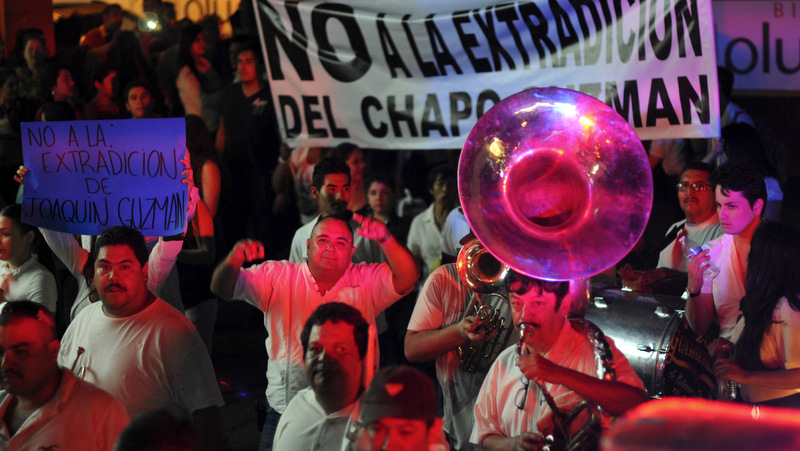 People play music and march in support of jailed top drug boss Joaquin Guzman Loera, El Chapo in the city of Culiacan, Mexico. A Large Sign Reads No to the extradition of Chapo Guzman in Spanish.