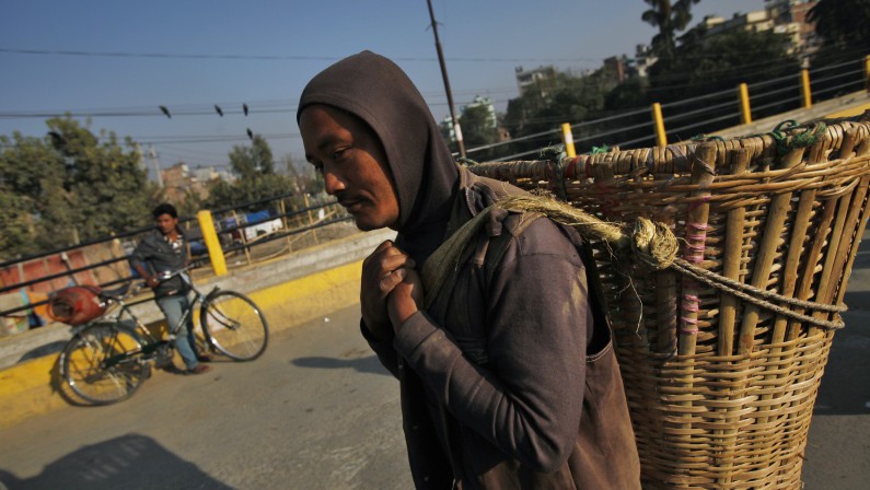 A Nepalese man carries vegetables in a basket to sell at a market in Katmandu, Nepal, Wednesday, Nov. 27, 2013. (AP Photo/Niranjan Shrestha)