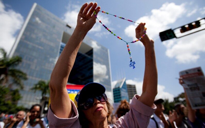 A demonstrator holds up a rosary during a protest