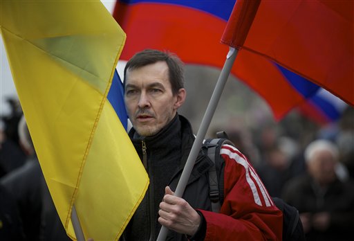 A demonstrator carries Russian and Ukrainian flags during a march to oppose president Vladimir Putin's policies in Ukraine, in Moscow, Saturday, March 15, 2014. Large rival marches have taken place in Moscow over Kremlin-backed plans for Ukraines province of Crimea to break away and merge with Russia. More than 10,000 people turned out Saturday for a rally in the center of the city held to oppose what many demonstrators described as Russias invasion of the Crimean Peninsula. In a nearby location, a similar sized crowd voiced its support for Crimeas ethnic Russian majority, who Moscow insists is at threat from an aggressively nationalist leadership now running Ukraine. (AP Photo/Alexander Zemlianichenko)