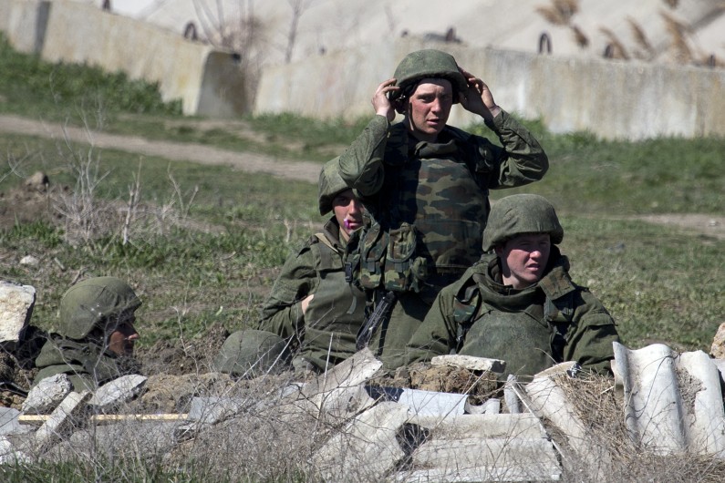 Pro- Russian soldiers in unmarked uniforms arrange a position near Ukrainian marines base in the city of Feodosia, Crimea, Sunday, March 23, 2014. On Sunday, the Russian Defense Ministry said the Russian flag was now flying over 189 military facilities in Crimea. It didn't specify whether any Ukrainian military operations there remained under Ukrainian control. (AP Photo/ Pavel Golovkin)