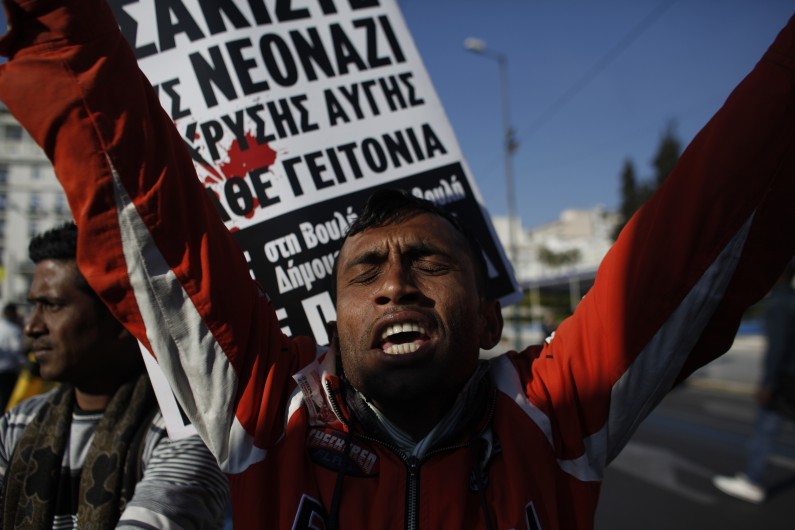 An immigrant shouts slogans during an anti-racist protest in Athens on Saturday, March 22, 2014, with sign in background reading "Smash the Neo Nazis of Golden Dawn in every neighbourhood".  About 5,000 people marched through central Athens Saturday to celebrate the International Day for the Elimination of Racial Discrimination.  (AP Photo/Kostas Tsironis)