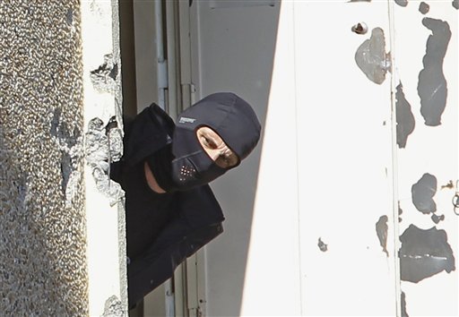 FILE -  In this March 23, 2014 file photo, a masked police officer searches for clues at  terrorist Mohamed Merah's apartment building in Toulouse, southern France. To stop the stream of French youths pursuing jihad in Syria, France is preparing to do something it has never done before: Tackle terrorism at its roots before it starts, by involving schools, parents and local Muslim leaders, The Associated Press has learned. Memories are still fresh of the radical Islamic Frenchman Merah who gunned down children at a Toulouse Jewish school in 2012, after training in Afghanistan and Pakistan. (AP Photo/Remy de la Mauviniere)