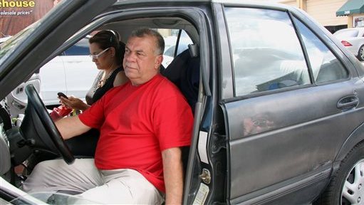 In this Wednesday, March 5, 2014, Carlos Salamanca tries to start his car in Miami. Salamanca fled Venezuela's increasingly political turmoil with his family in January. He is now living largely out of an old Nissan he purchased for $1,000. Salamanca was a small business owner in Venezuela and said he fled after receiving threats against his family. (AP Photo/Christine Armario)