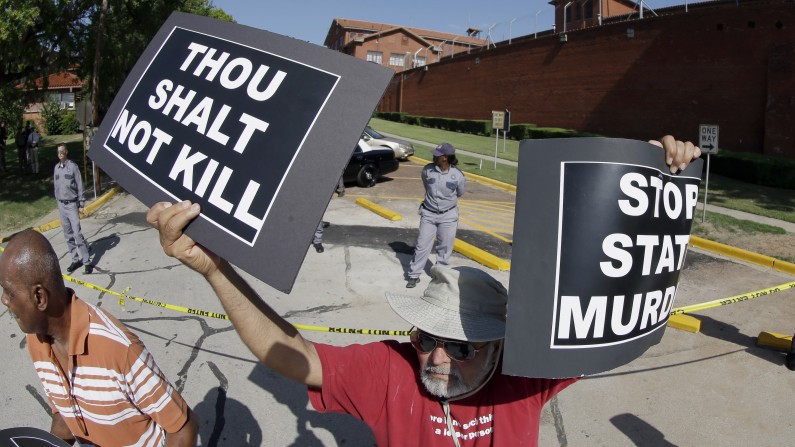 Habi Jawad holds up his signs to protest the execution of Kimberly McCarthy on Wednesday, June 26, 2013 outside the Texas Department of Criminal Justice Huntsville Unit, where the death chamber is located, in Huntsville, Texas. If McCarthy is put to death as planned, she would become the 500th person executed in Texas since the state resumed carrying out the death penalty in 1982. The 52-year-old also would be the first woman executed in the U.S. since 2010. (AP Photo/David J. Phillip)