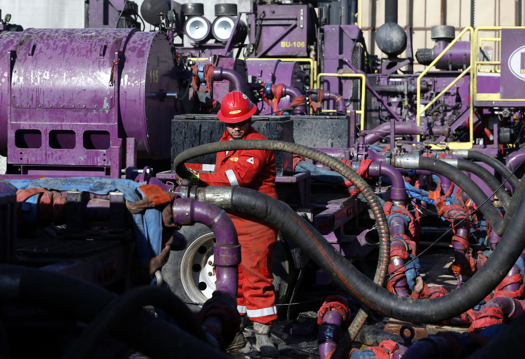 A worker adjusts hoses during a hydraulic fracturing operation at an Encana Corp. oil well, near Mead, Colo, March 25, 2014.
