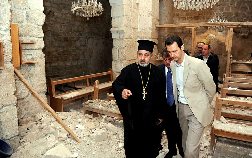 Syrian President Bashar al-Assad, right, checks a church damaged by militants during a visit to the Christian village of Maaloula, near Damascus, Syria. April 20, 2014. (Syrian Presidency via Facebook)