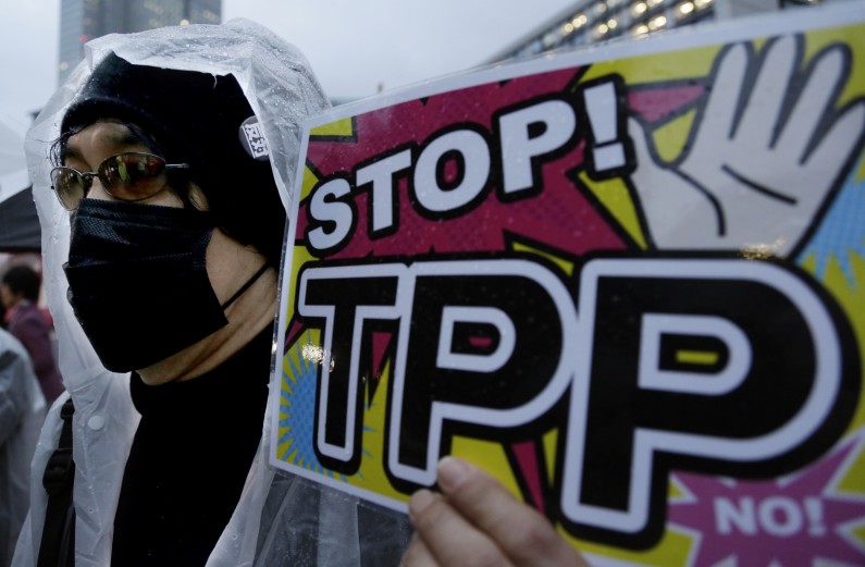 A protester holds a slogan during a rally against the Trans-Pacific Partnership (TPP) in Tokyo, Tuesday, April 22, 2014. (AP Photo/Shizuo Kambayashi)