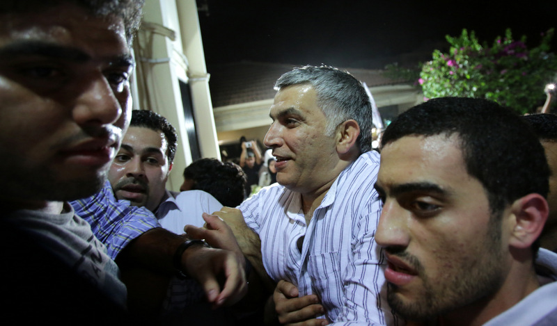 Nabeel Rajab, head of the Bahrain Center for Human Rights, is helped to his front door as well-wishers push in to greet him at his home in Bani Jamra, Bahrain, on Saturday, May 24, 2014, after spending nearly two years behind bars. Rajab was charged sentenced Thursday with an additional six months behind bars for insulting the government on Twitter.
