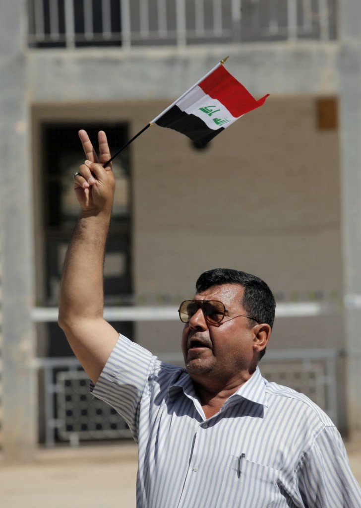 An Iraqi man waves a national flag before casting his vote at a polling station in the Shiite holy city of Najaf, 100 miles (160 kilometers) south of Baghdad, Iraq, Wednesday, April 30, 2014. Iraq is holding its third parliamentary elections since the U.S.-led invasion that toppled dictator Saddam Hussein. More than 22 million voters are eligible to cast their ballots to choose 328 lawmakers out of more than 9,000 candidates. (AP Photo/Jaber al-Helo)