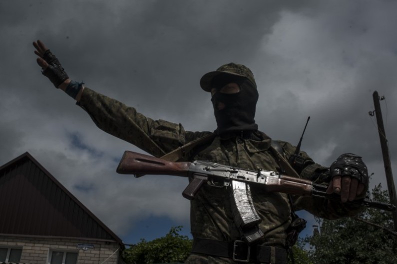 A pro-Russian fighter stands guard at a checkpoint in Slovyansk, eastern Ukraine, Thursday, June 12, 2014. The city has been an epicenter of a nearly two-month standoff between Ukrainian forces and pro-Russian rebels, who have seized administrative buildings, police stations and border posts across the region. (AP Photo/Evgeniy Maloletka)