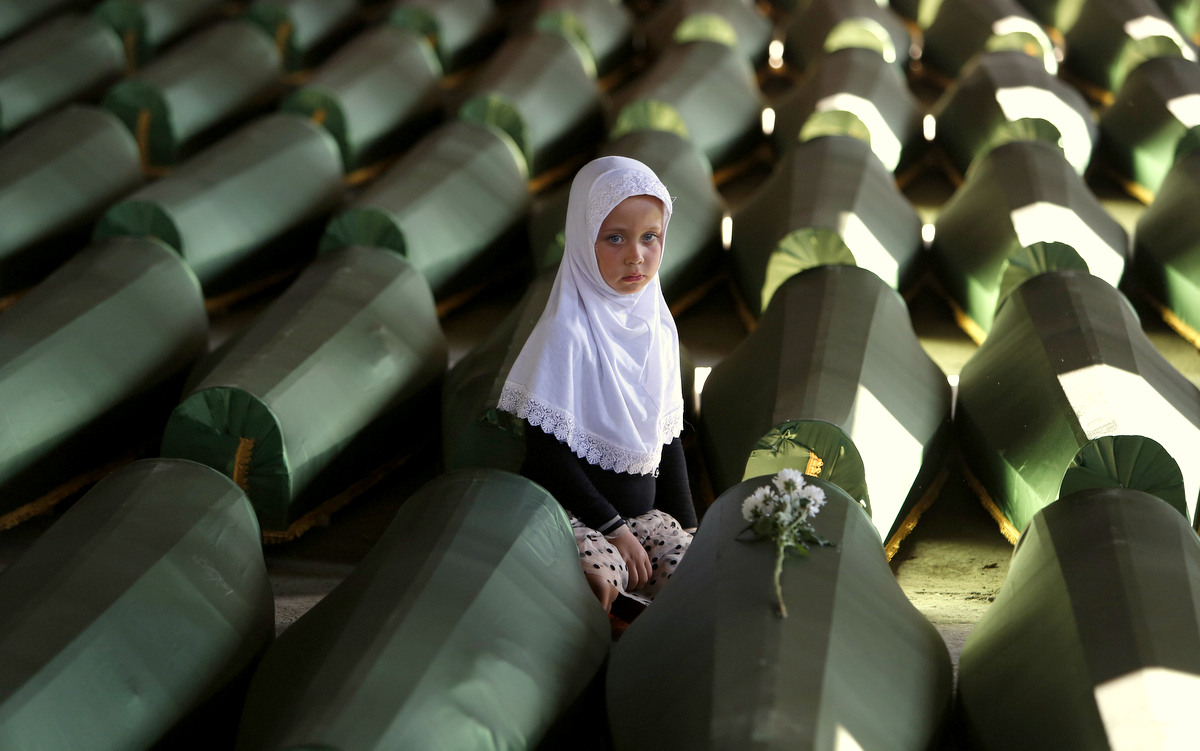 Ema Hasanovic, a young Bosnian Muslim girl, pays her respects near to the coffin of her uncle, in the Srebrenica massacre Memorial center in Potocari, 200 km northeast of Sarajevo, Bosnia, Wednesday, July 9, 2014. (AP/Amel Emric)