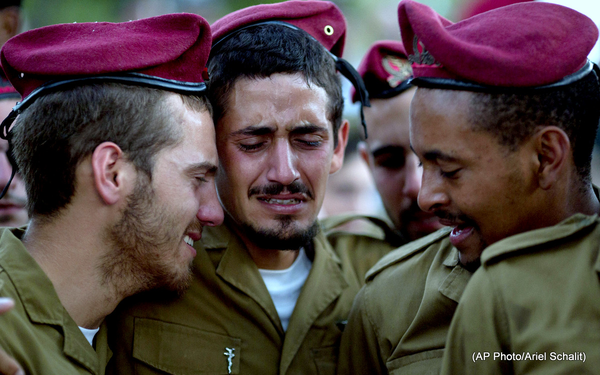 Israeli soldiers of the Paratroopers Brigade mourn over the grave of Sgt. Bnaya Rubel during his funeral at the military cemetery in Holon, Israel, Sunday, July 20, 2014. Rubel was killed during the Israeli assault on Gaza, dubbed "Operation protective edge."