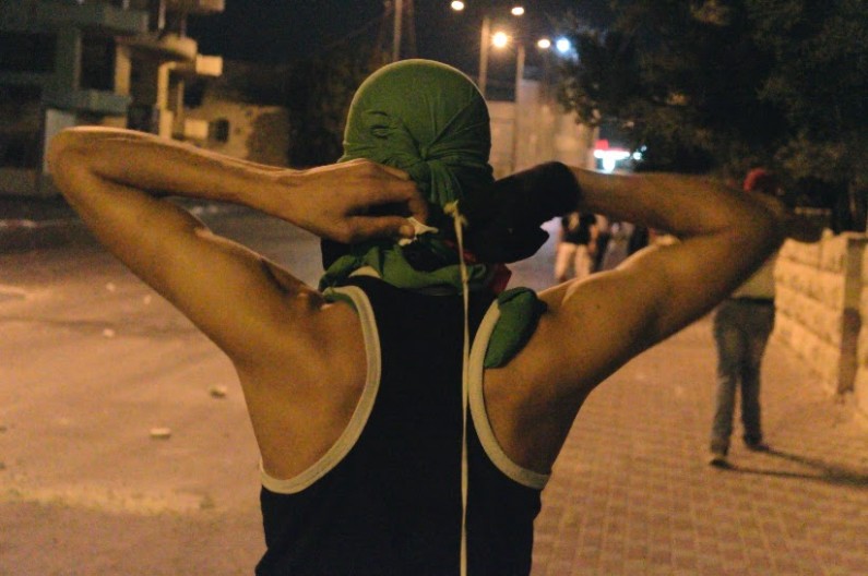 Palestinian protester ties clothing over his face to protect his identity to the IDF.