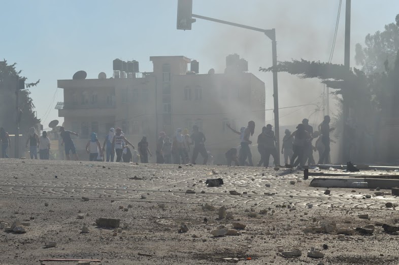 Tear Gas and smoke saturate the air as young men from Shufat hide of a side road from IDF. (Photo by Matthew Vickery for Mint Press)