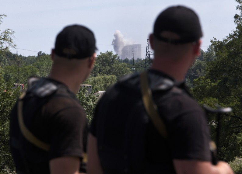 Self-proclamed Donetsk People's Republic policemen watch shelling in Shakhtarsk, Donetsk region, eastern Ukraine on Monday, July 28, 2014. An international police team abandoned its attempt to reach the crash site of a Malaysia Airlines plane for a second day running Monday as clashes raged in a town on the road to the area.(AP Photo/Dmitry Lovetsky)