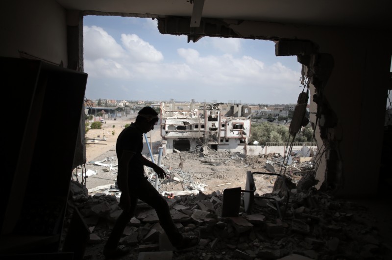 A Palestinian walks through a destroyed house in Rafah's district of Shawkah in the southern Gaza Strip, Tuesday, Aug. 5, 2014. The attack at the Shawkah district east of the Gaza town of Rafah drew what was by far the heaviest shelling by the Israeli military in the Gaza war, killing nearly 100 people that day alone and instantly unraveling a three-day ceasefire shortly after it came into force. (AP Photo/Khalil Hamra)