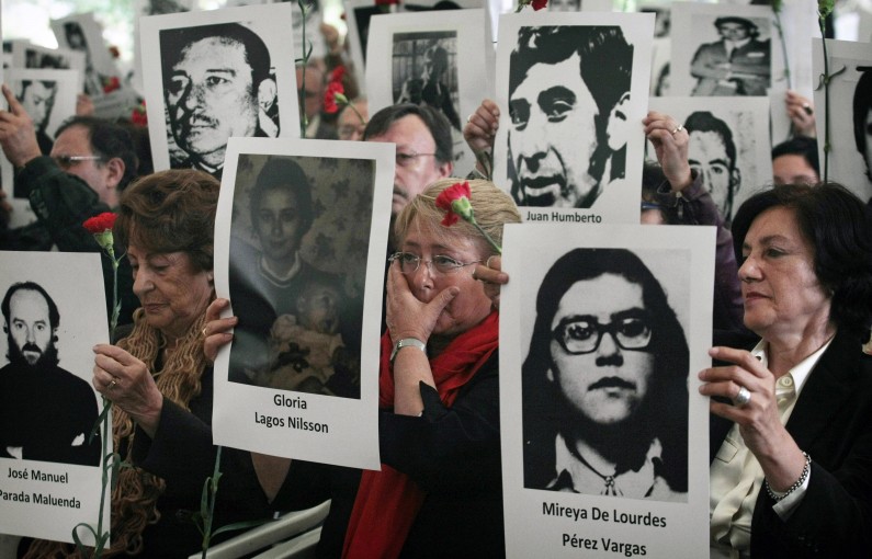 Chile's former President Michelle Bachelet, center, wipes a tear as she stands with her mother Angela Jeria, left, and Margarita Romero, president of the Villa Grimaldi organization, right, all holding photographs of victims of the dictatorship of Gen. Augusto Pinochet, as she attends a ceremony marking the 40th anniversary of his military coup in Santiago, Chile, Tuesday, Sept. 10, 2013. The ceremony is held at the Villa Grimaldi compound, which was at one time a detention and torture center where Bachelet and her mother were taken after their arrests. Bachelet's father, a general, was tortured to death for opposing the Sept. 11, 1973 coup. (AP Photo/Luis Hidalgo)