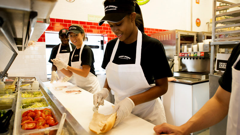 3 Jimmy John employees making sandwiches.