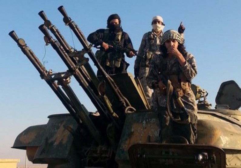 This image posted by the Raqqa Media Center shows fighters from the Islamic State group on top of a military vehicle with anti-aircraft guns in Raqqa, Syria, Thursday, Aug 7, 2014. The Islamic State militants seized the Brigade 93 base overnight after days of heavy fighting, according to the Syrian Observatory for Human Rights and the Raqqa Media Center, an activist collective. The base lies some 40 miles (60 kilometers) from the provincial capital of Raqqa, a stronghold for the Islamic State group. (AP Photo/Raqqa Media Center)