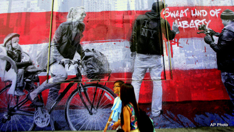 Pedestrians pass the mural "9/11" that is installed on the facade of the Century 21 department store, Wednesday, Sept 10, 2014, in New York.