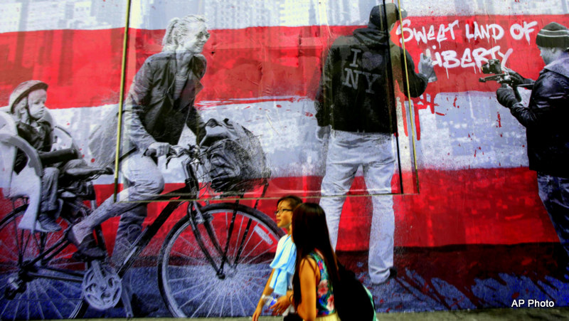 Pedestrians pass the mural "9/11" that is installed on the facade of the Century 21 department store, Wednesday, Sept 10, 2014, in New York.
