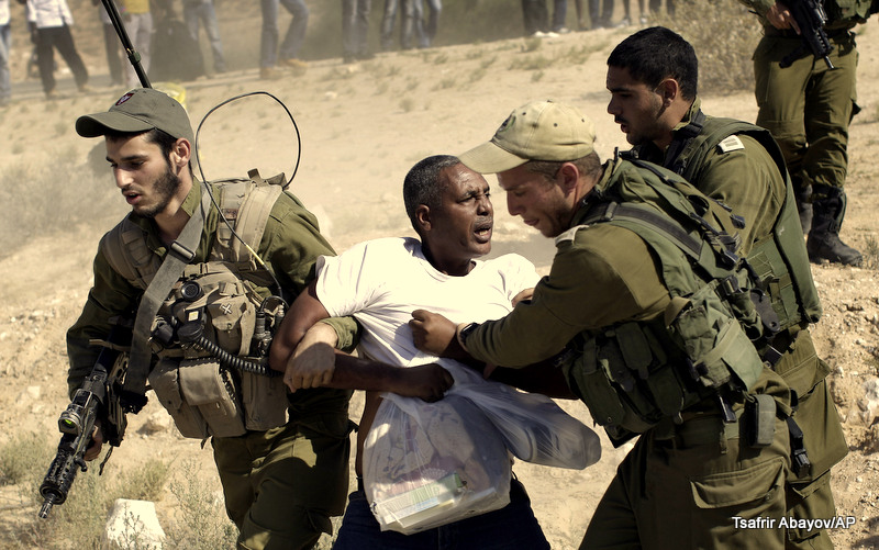 In this Friday, June 27, 2014 file photo, African migrants clash with Israeli soldiers after they left Holot detention center in southern Israel and walked towards the Border with Egypt near the southern Israeli Kibbutz of Nitzana.