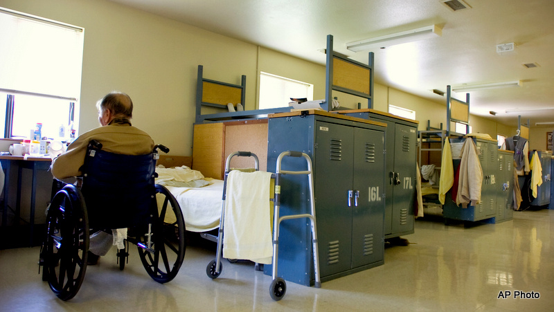 An inmate sits in is his wheelchair near his bed in the assisted living facility at the Coyote Ridge Corrections Center in Connell, Wash. Tuesday, Aug. 3, 2010. 