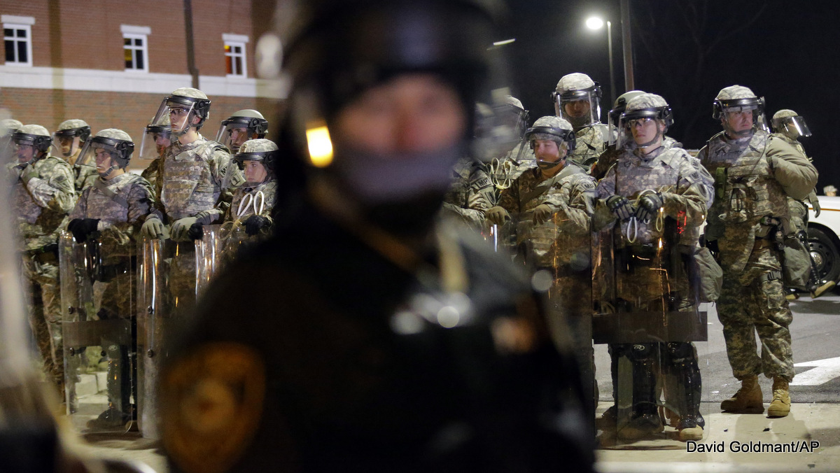 La Guardia Nacional de Missouri se alinea detrás de los oficiales de policía que monitorean a los manifestantes frente al Departamento de Policía de Ferguson el martes 25 de noviembre de 2014, en Ferguson, Missouri. la decisión de un gran jurado de no acusar al oficial de policía Darren Wilson en el tiroteo fatal de Michael Brown, un caso que ha inflamado las tensiones raciales en los EE. UU.