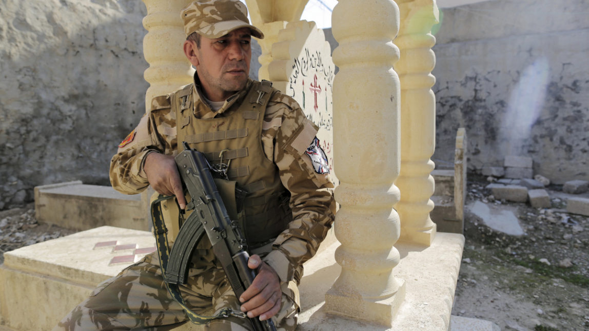 A Dwekh Nawsha militia member sits on top of a tombstone inside a 200-year-old monastery in the Christian village of Bakufa, 30 kilometers (18.6 miles) north of Mosul, Iraq, Wednesday, Nov. 12, 2014. Dwekh Naswha, or "self sacrifice" in Assyrian, is a Christian militia recently formed by volunteers to protect Christian territories in the Nineveh Province in Iraq. (AP/Bram Janssen)