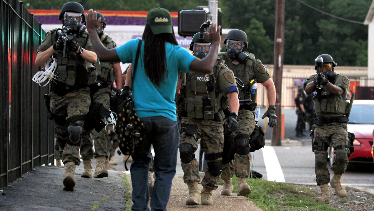 Police wearing riot gear walk toward a man with his hands raised Monday, Aug. 11, 2014, in Ferguson, Mo. (Photo/Jeff Roberson,AP)