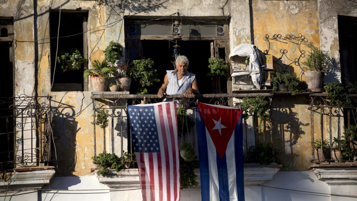 Javier Yanez stands on his balcony where he hung a U.S. and Cuban flag in Old Havana Cuba, Friday, Dec. 19, 2014