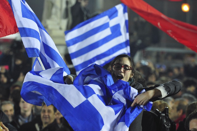 A woman waves a Greek flag during a speech by the leader of Syriza left-wing party Alexis Tsipras outside Athens University Headquarters, Sunday, Jan. 25, 2015. A triumphant Alexis Tsipras told Greeks that his radical left Syriza party's win in Sunday's early general election meant an end to austerity and humiliation and that the country's regular and often fraught debt inspections were a thing of the past. (AP Photo/Fotis Plegas G.)