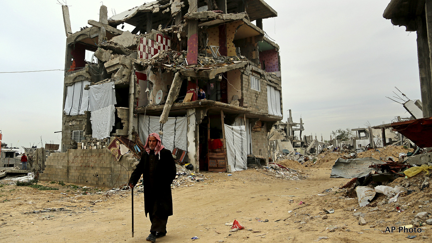 An elderly Palestinian walks past a destroyed building in Gaza